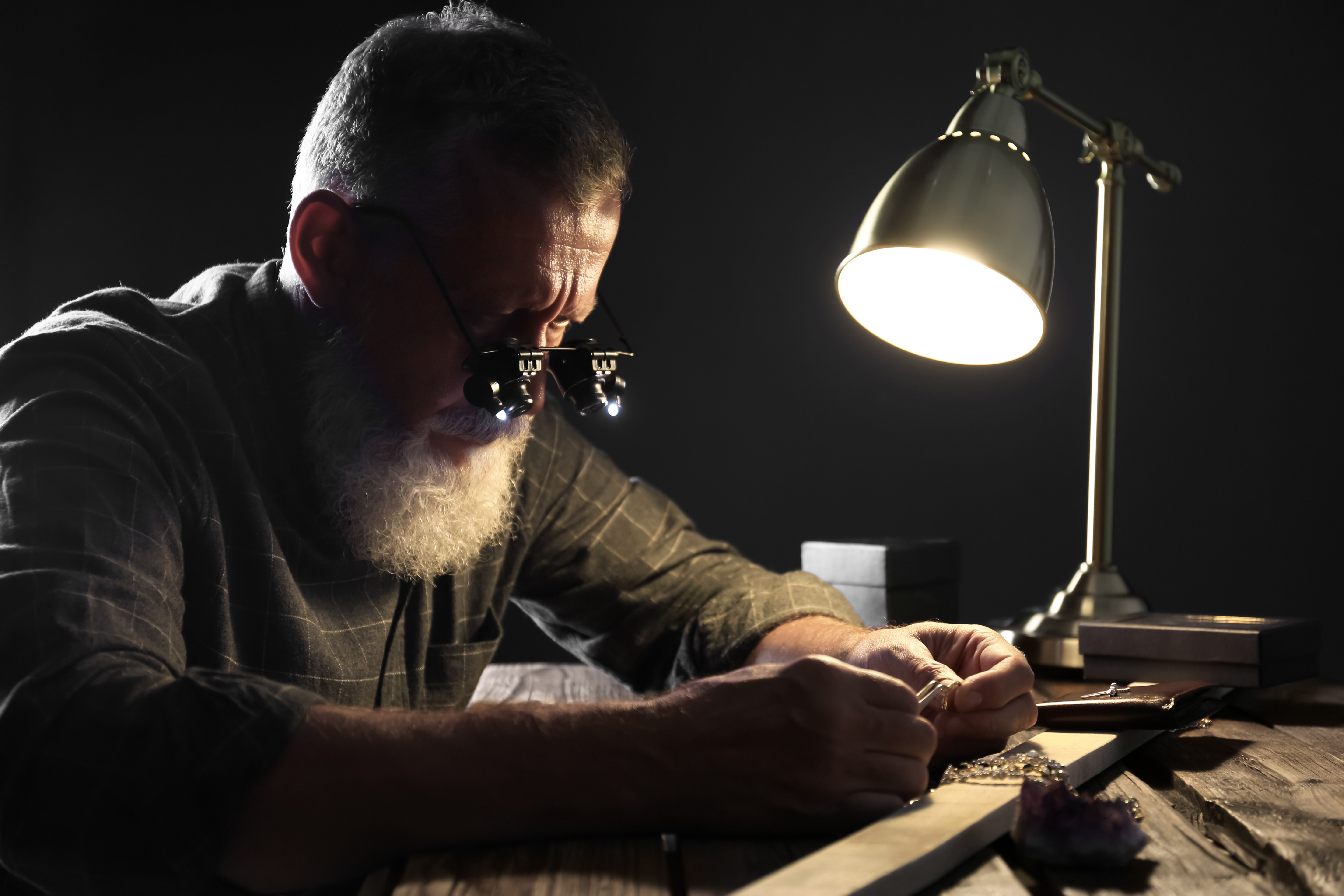 Hombre joyero evaluando un anillo de diamantes en un taller | Fuente: Shutterstock.com