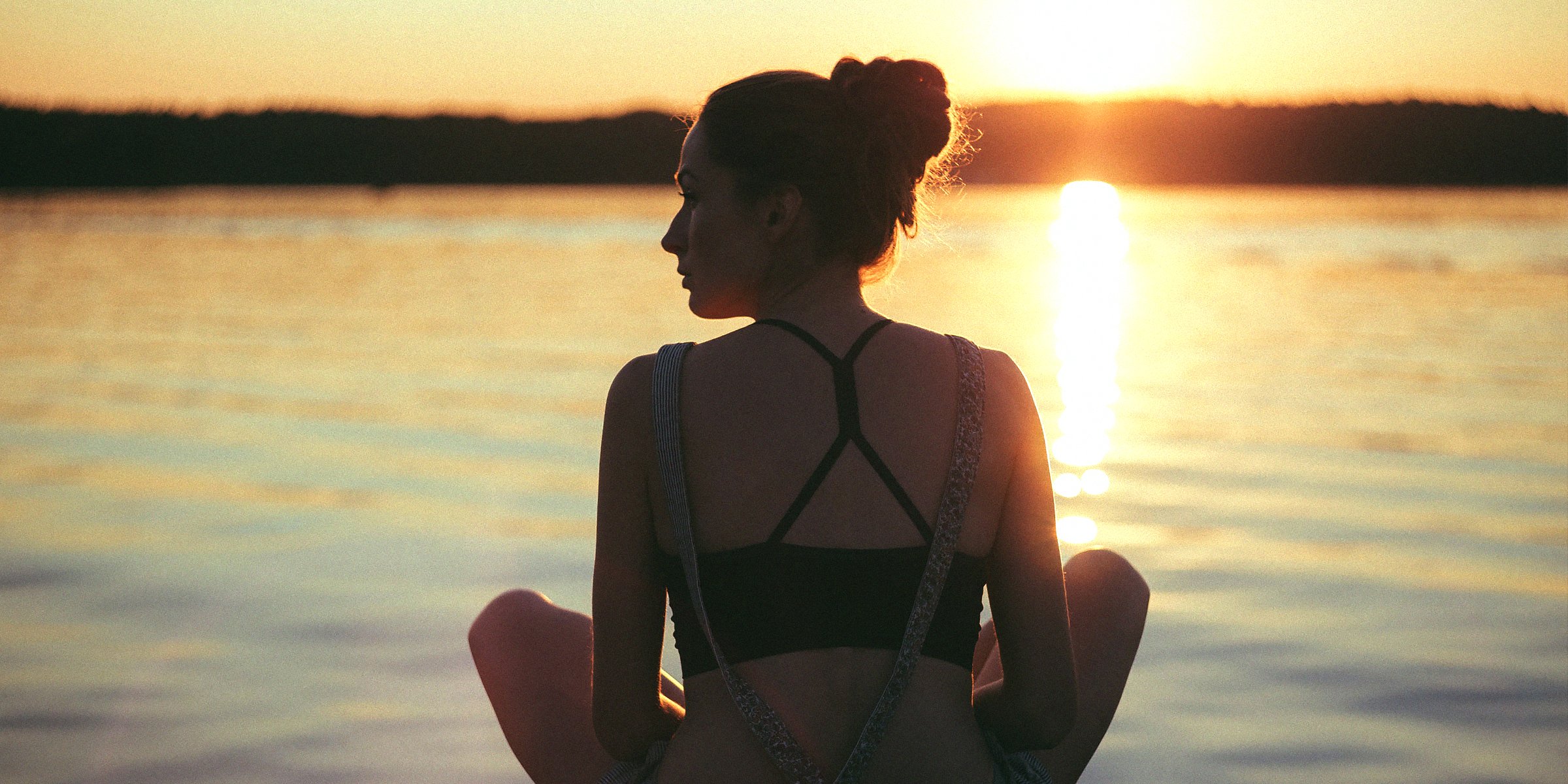 Unsplash | A woman sitting cross-legged in front of a lake