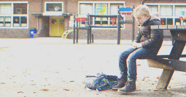 A kid sitting on a bench in the school playground | Source: Shutterstock