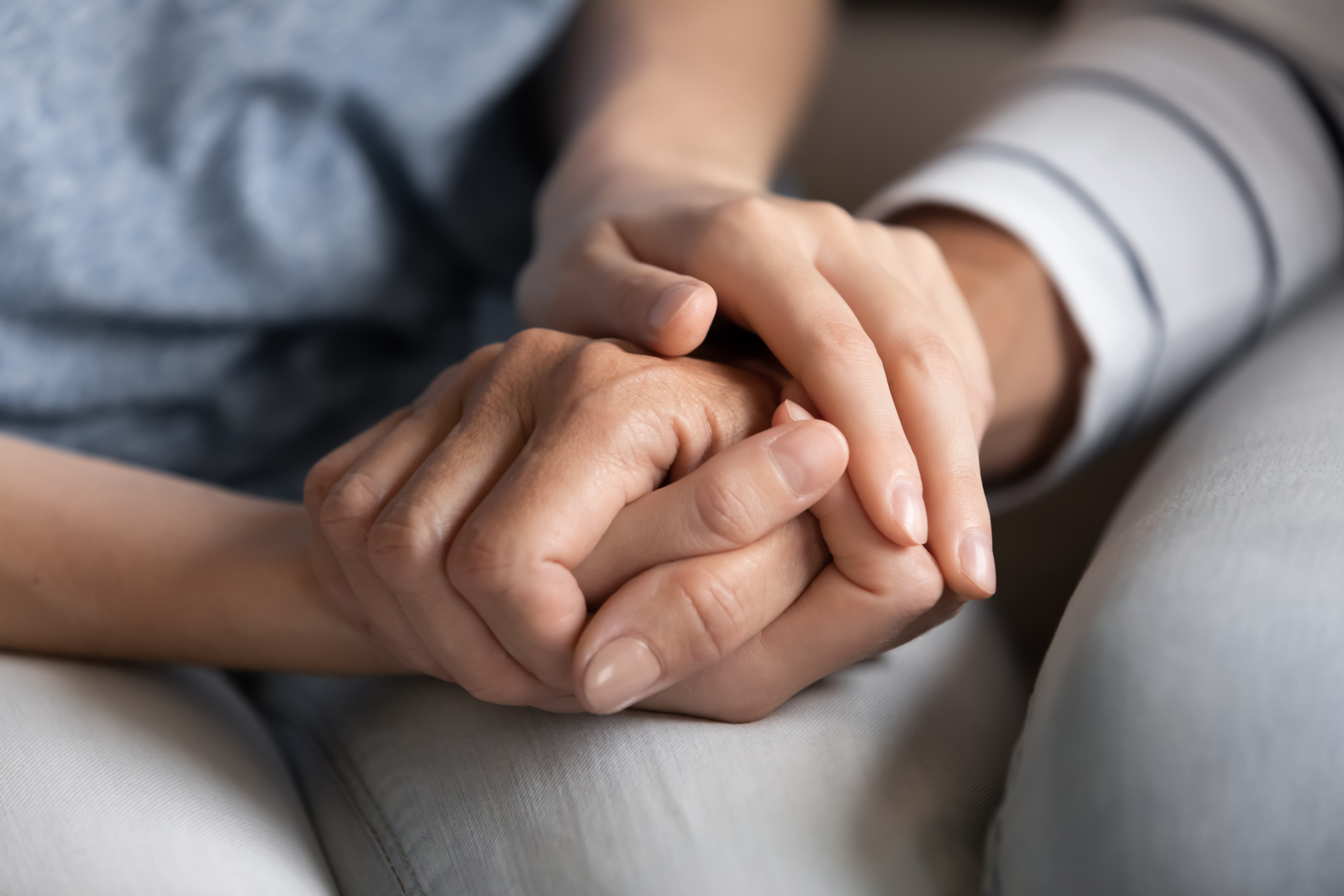 Primer plano de una mujer milenaria, hija adulta, nieta o amiga más joven, cogiendo con fuerza la mano de una madre anciana, abuela, pariente mayor o colega, ayudándola a superar los problemas de la vida. | Fuente: Shutterstock