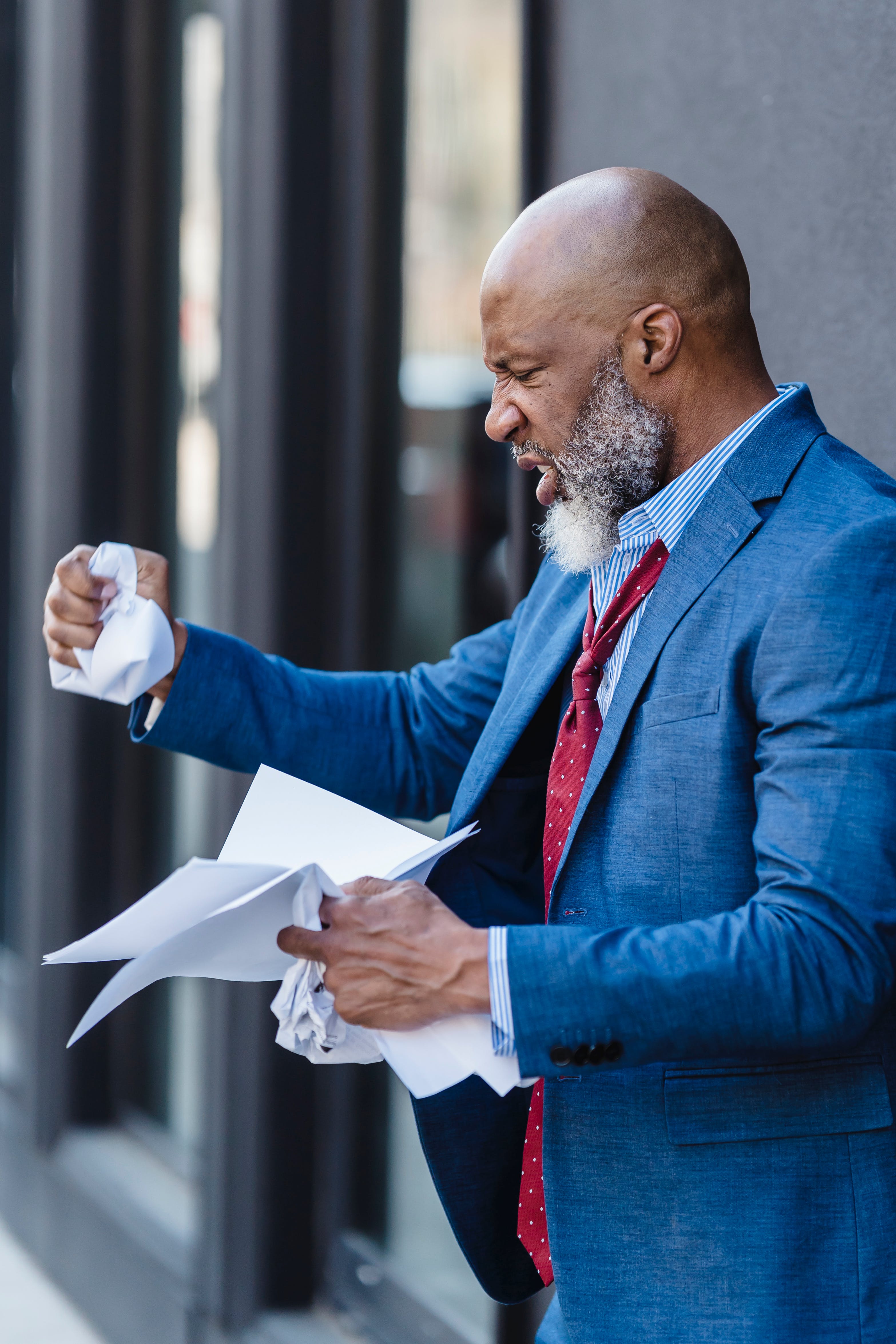 An angry business man crumpling documents. | Source: Pexels