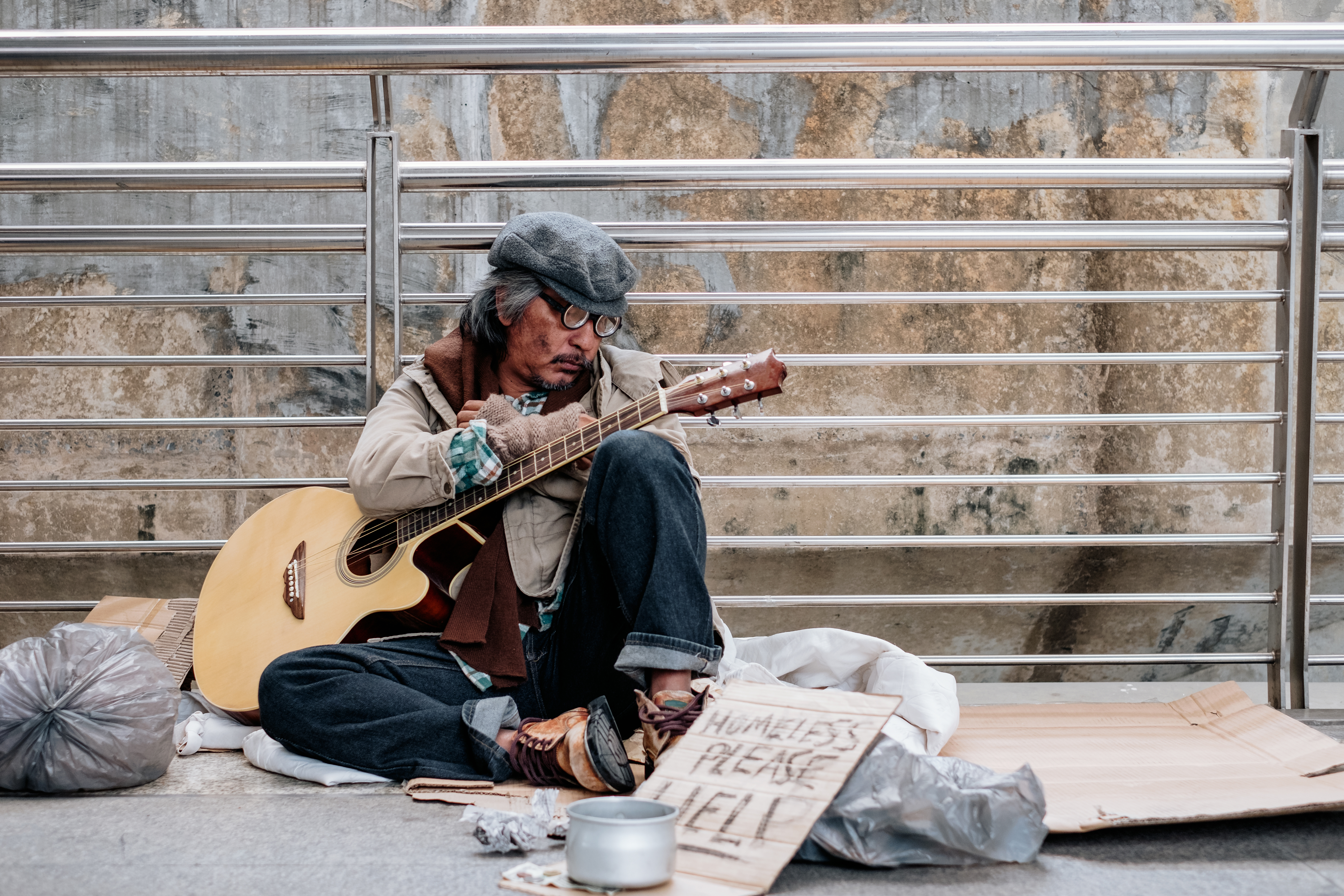 Indigente sentado con la guitarra en la mano. | Fuente: Shutterstock