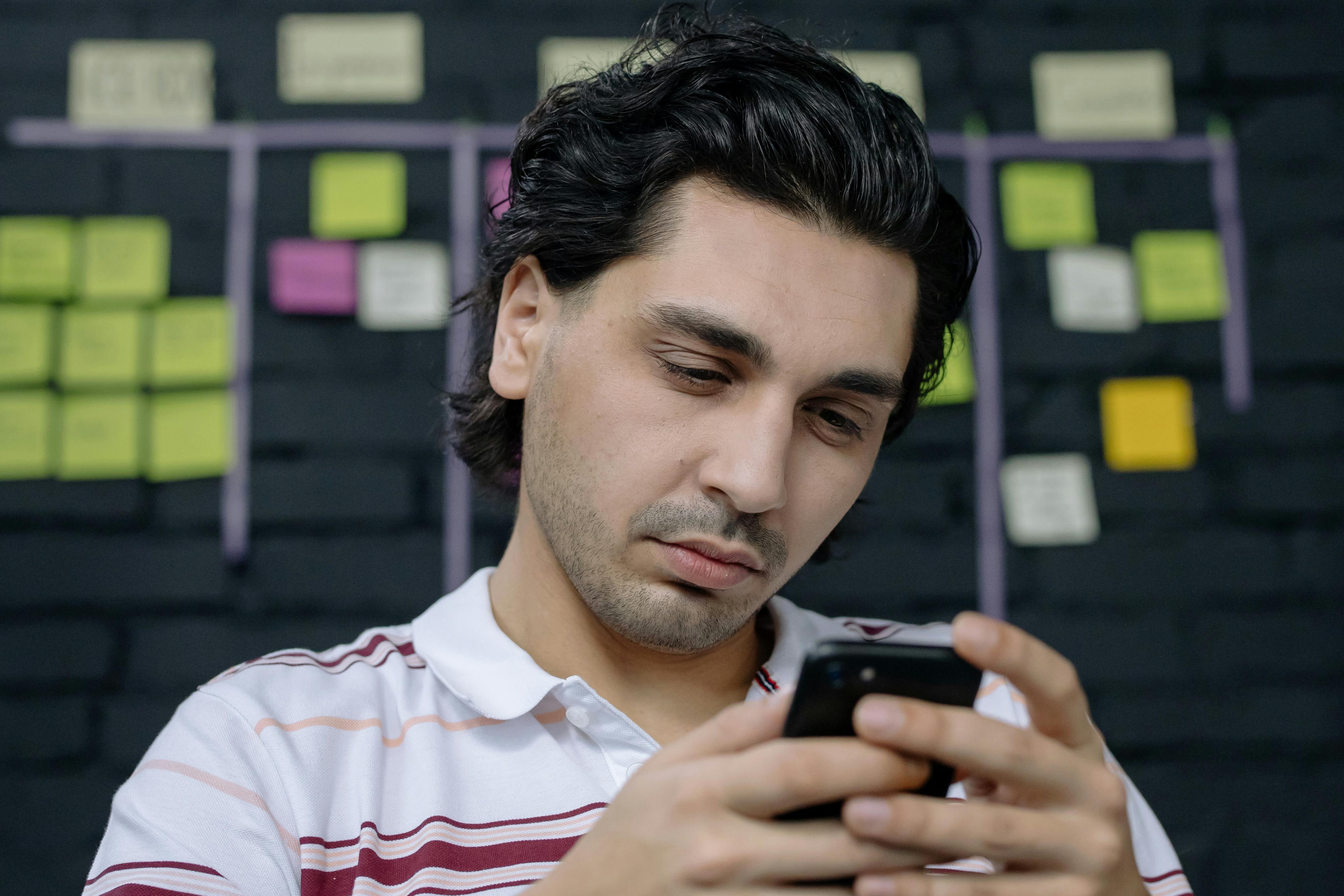 A man concentrating on something on his phone, photo taken on January 17, 2021. | Source: Pexels