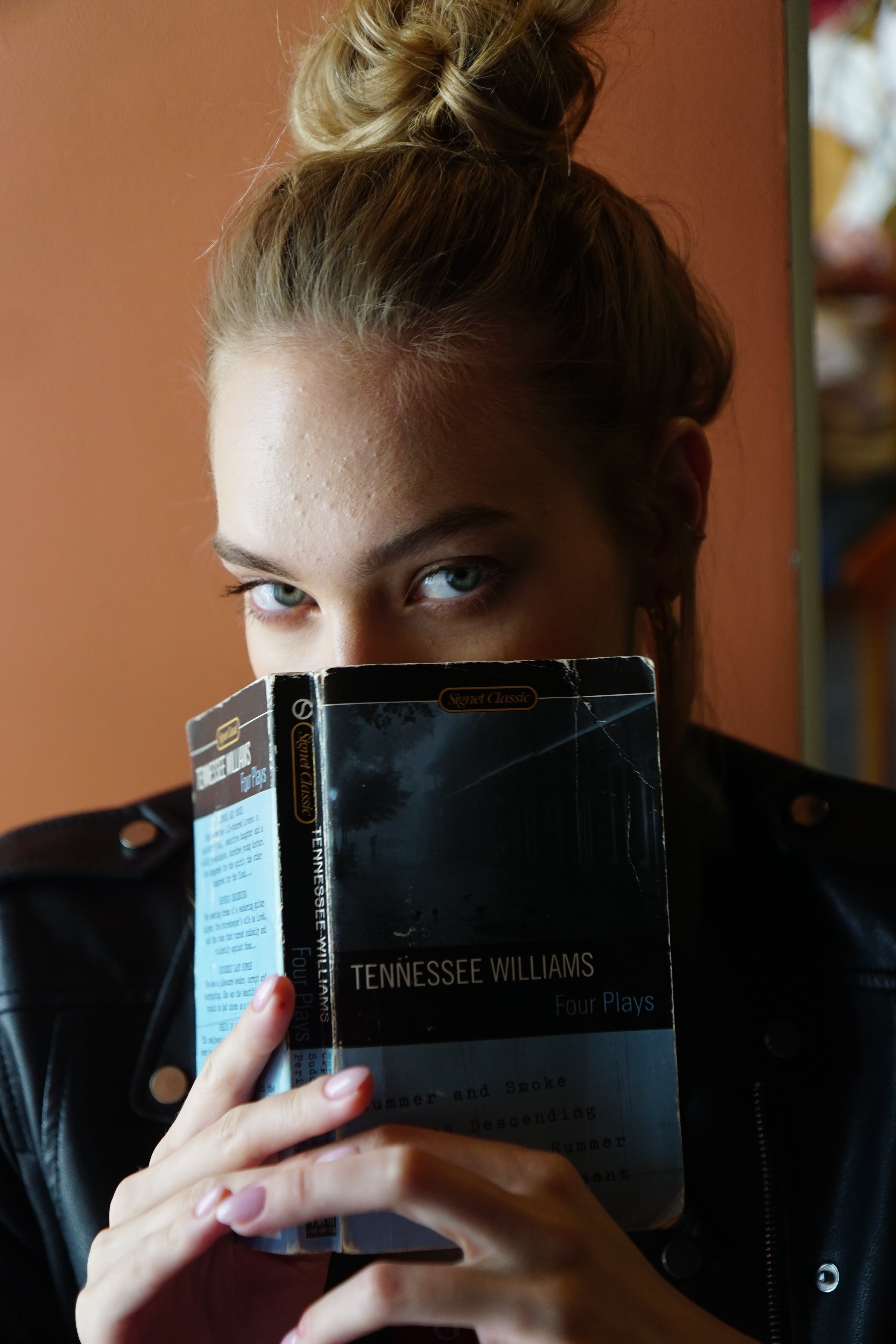 A woman holding a book in front of the bottom half of her face. | Source: Pexels