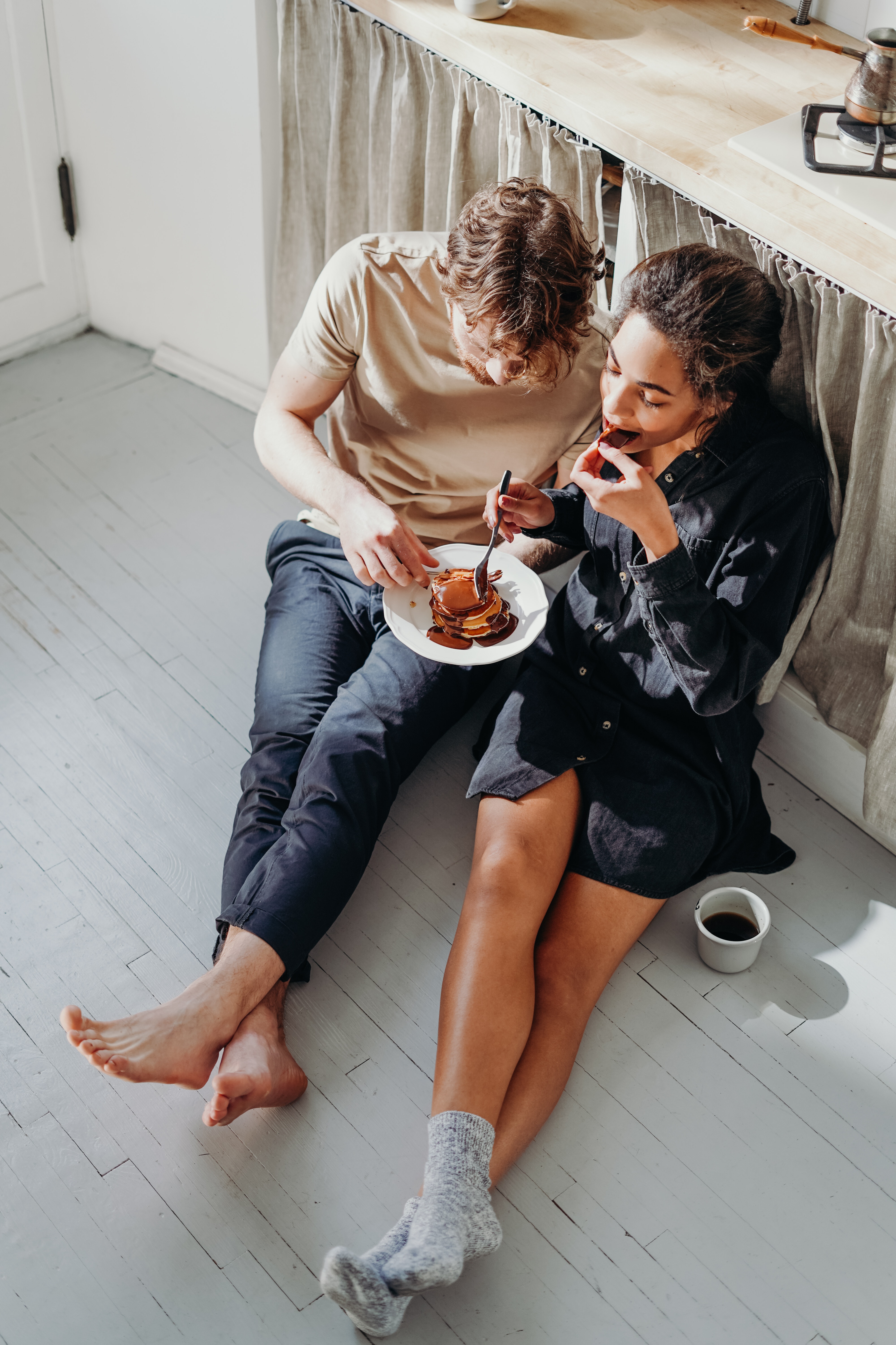 A couple eating pancakes while sitting on the floor. | Source: Pexels