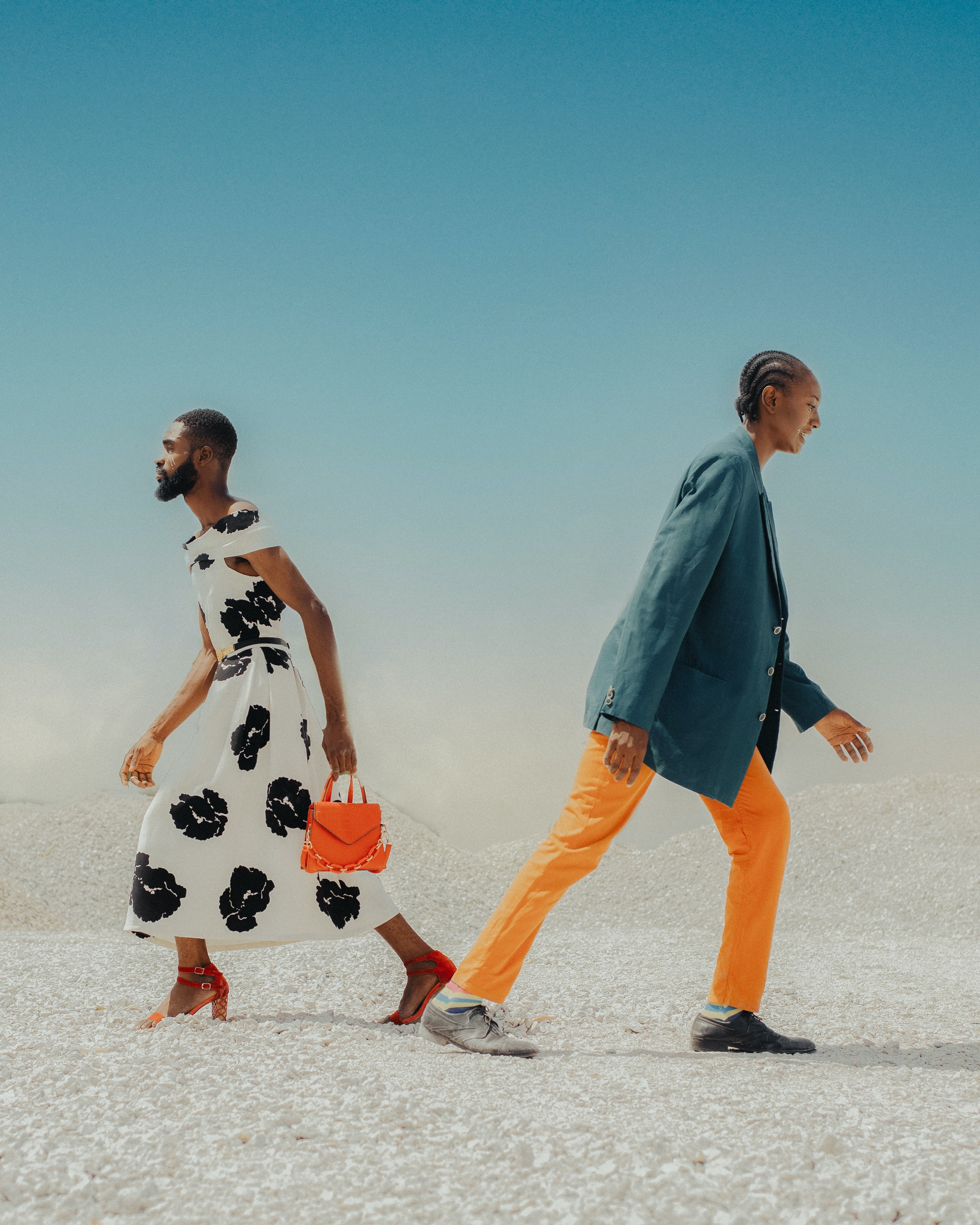 A woman wearing a suit and a man wearing a dress walking in opposite directions. | Source: Pexels