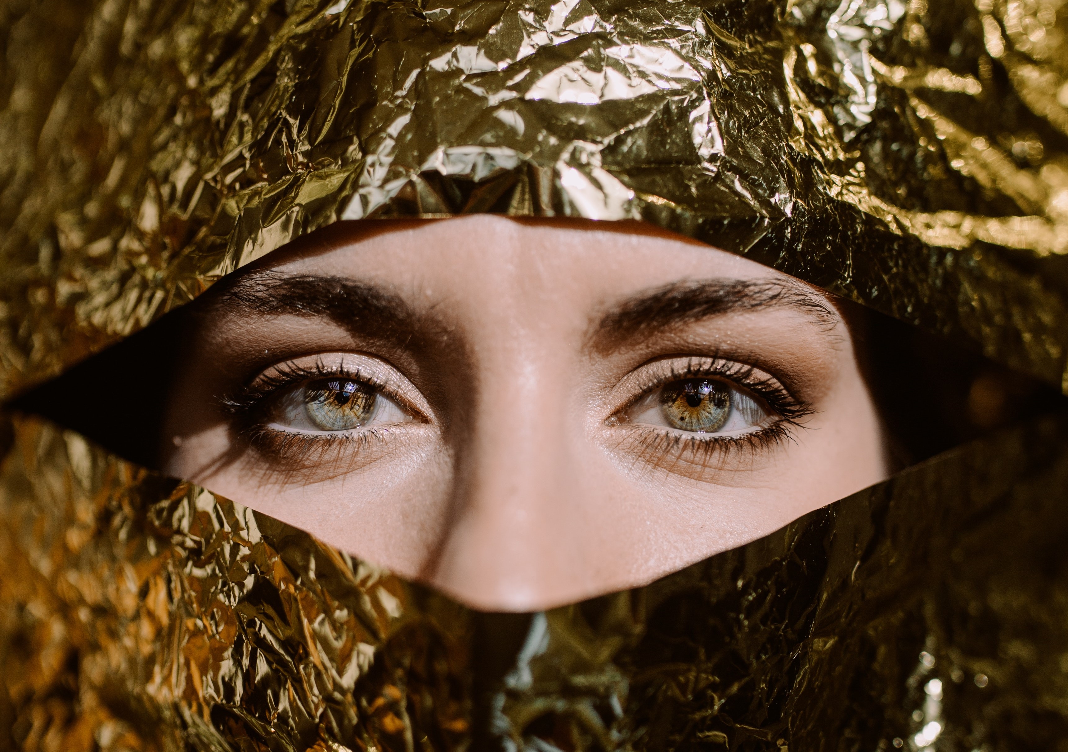 A woman looking through golden paper. | Source: Pexels