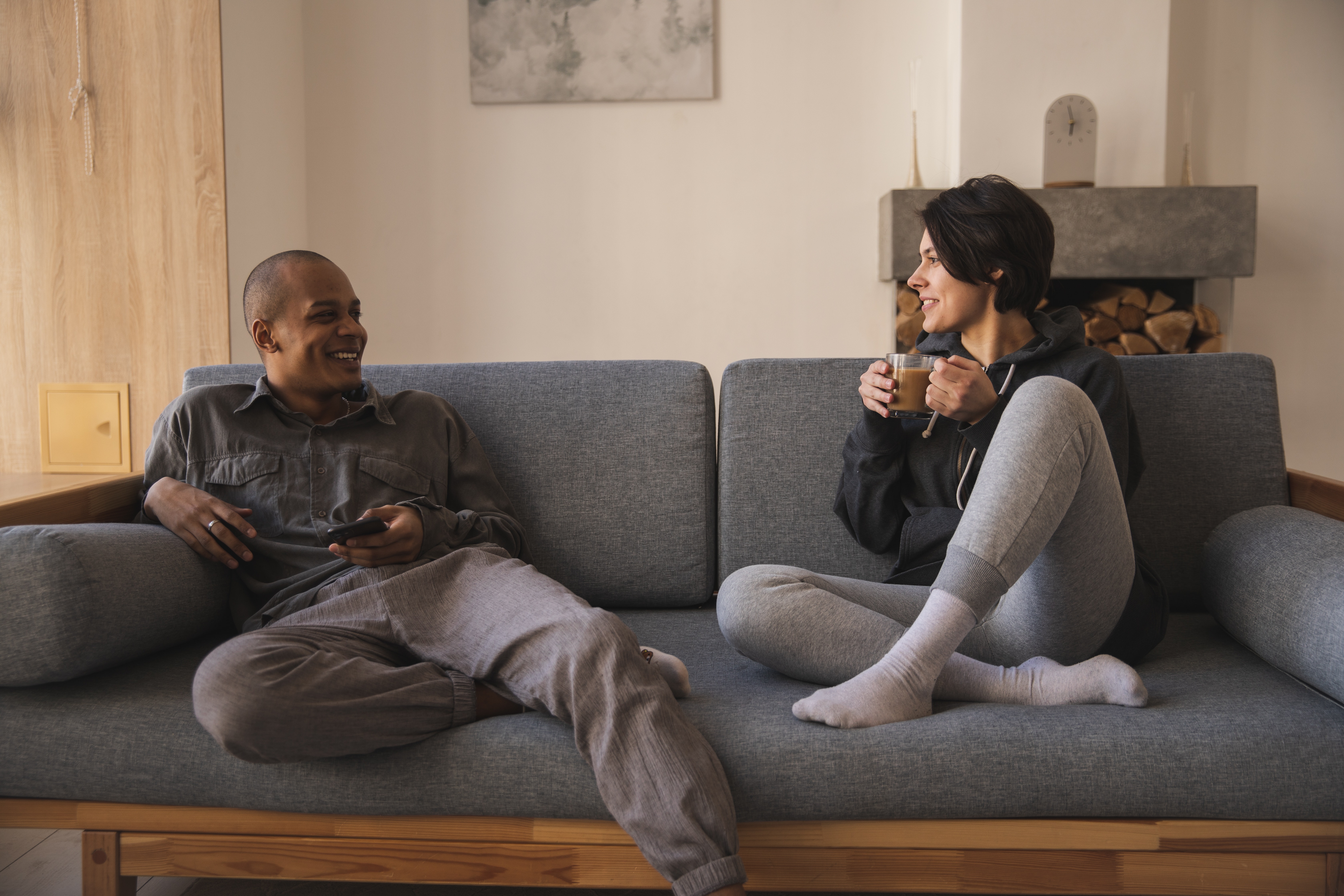 Happy young multiracial couple talking on sofa at home. | Source: Pexels