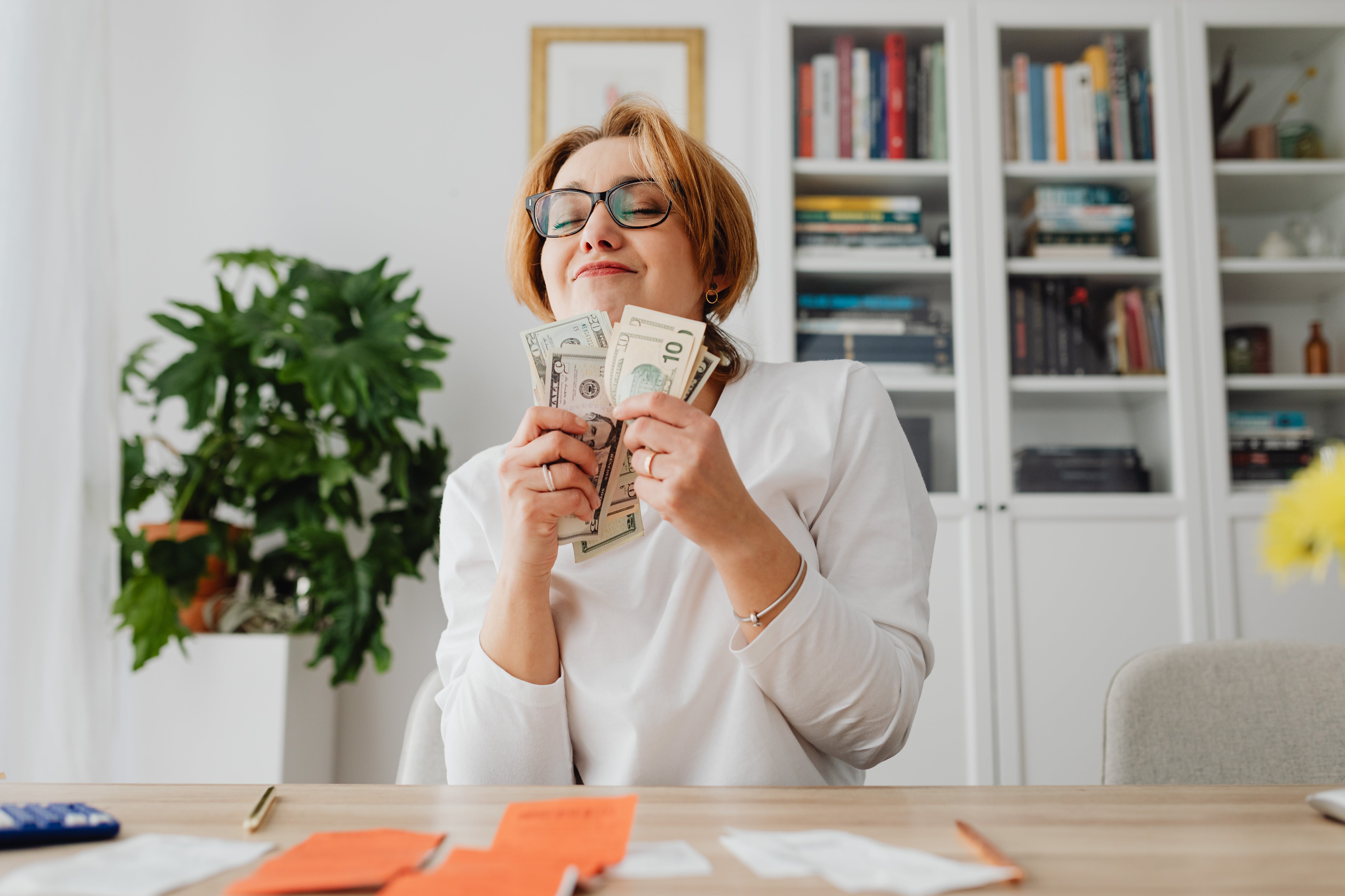 A woman holding money and smiling. | Source: Pexels