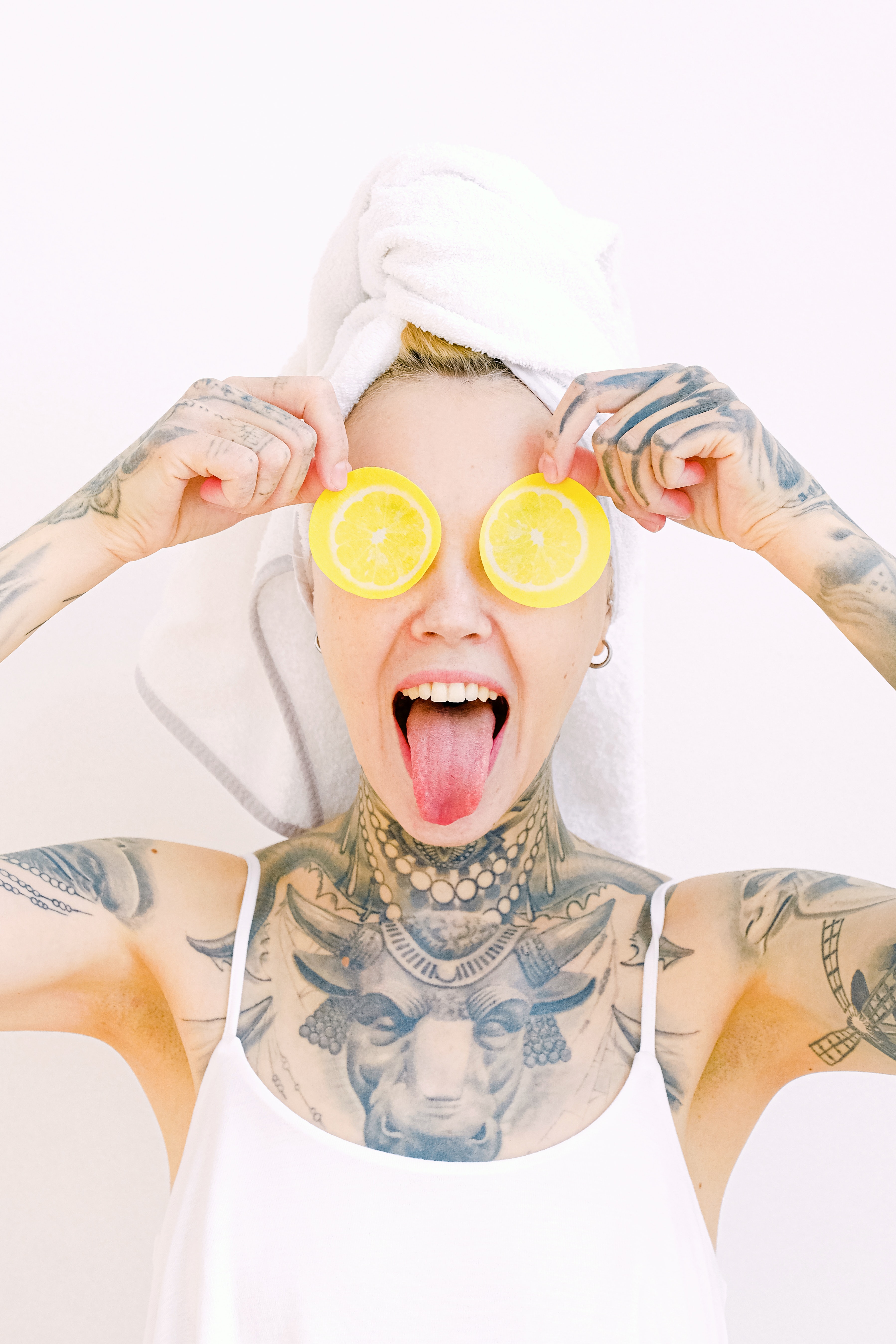 A woman holding lemon slices over her eyes and sticking her tongue out. | Source: Pexels