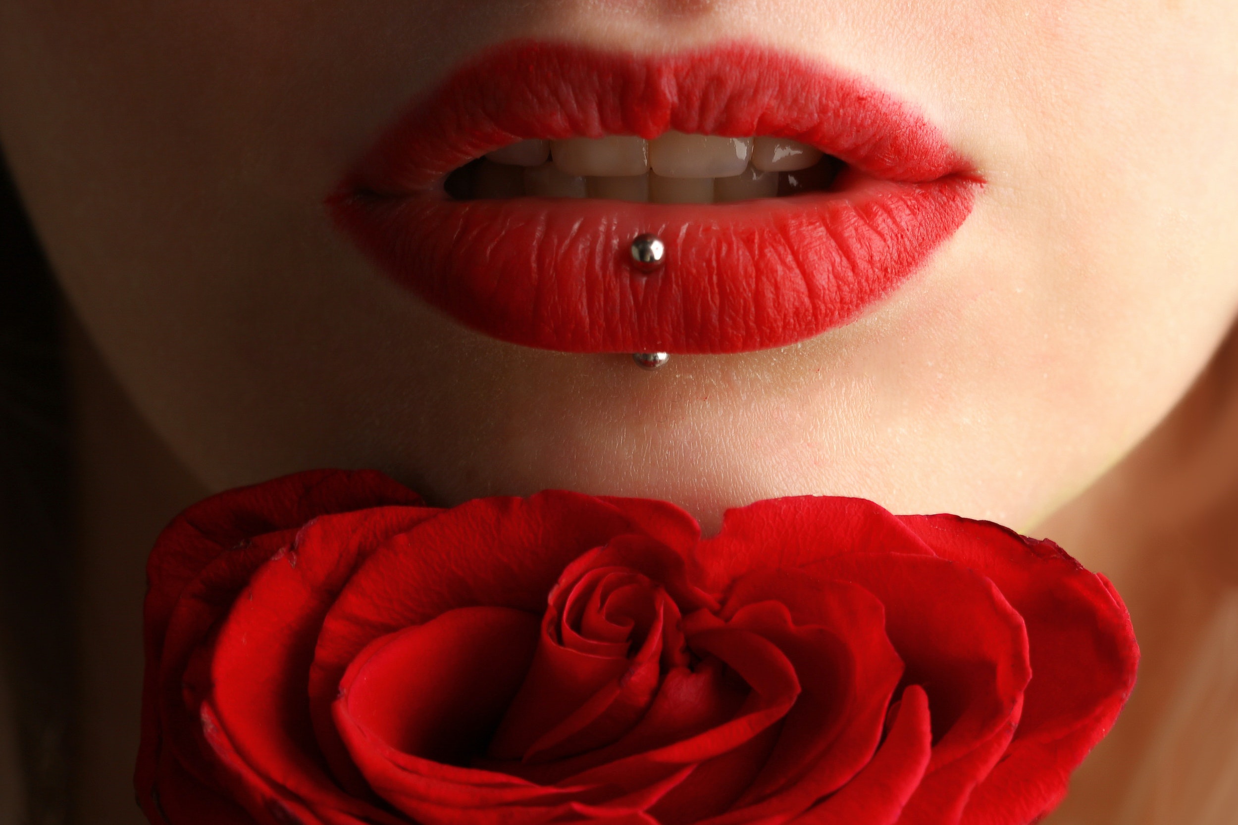 Red lips with a piercing and a red rose. │ Source: Pexels