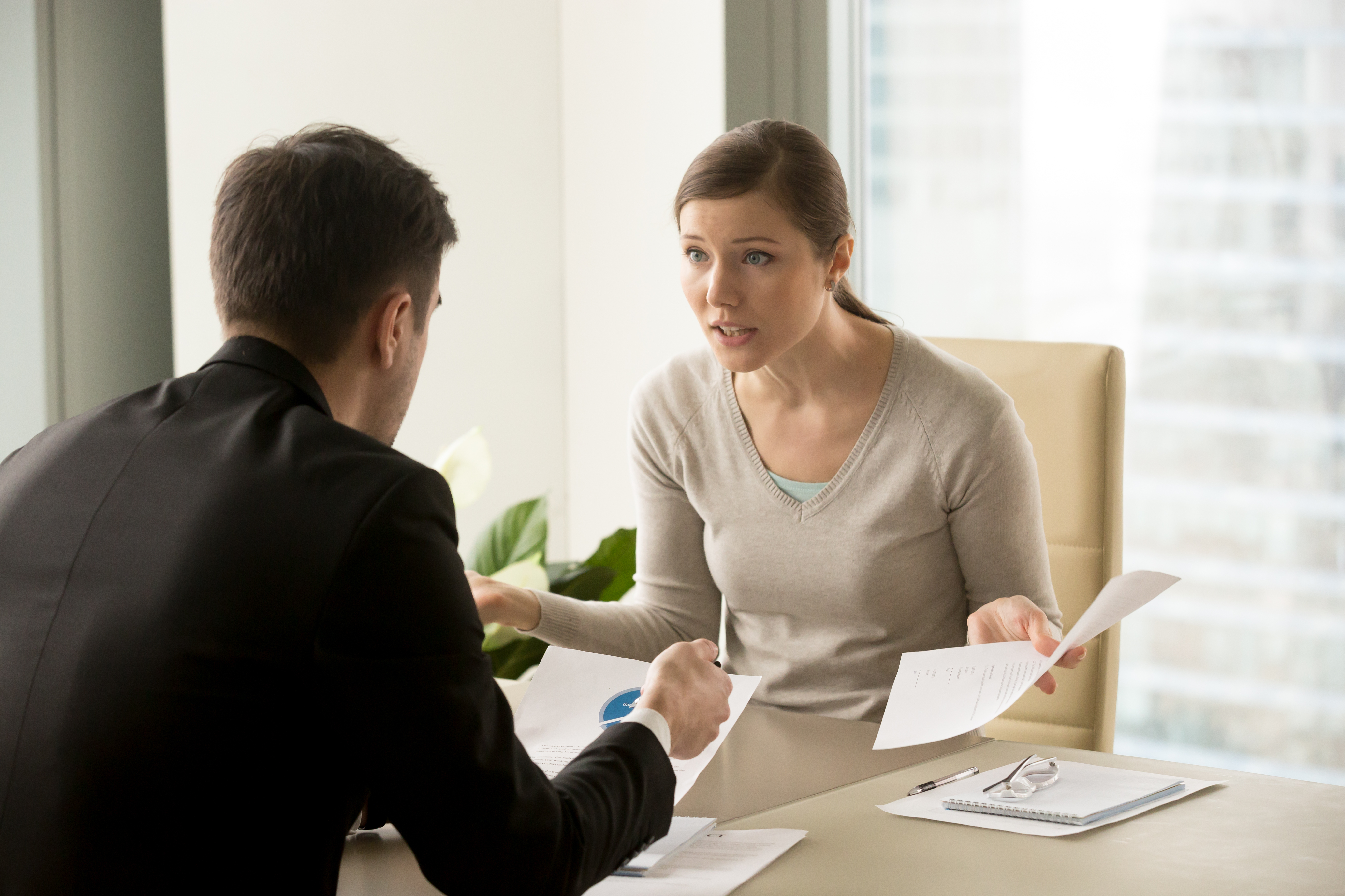 Una mujer discutiendo con un hombre en una oficina | Fuente: Shutterstock