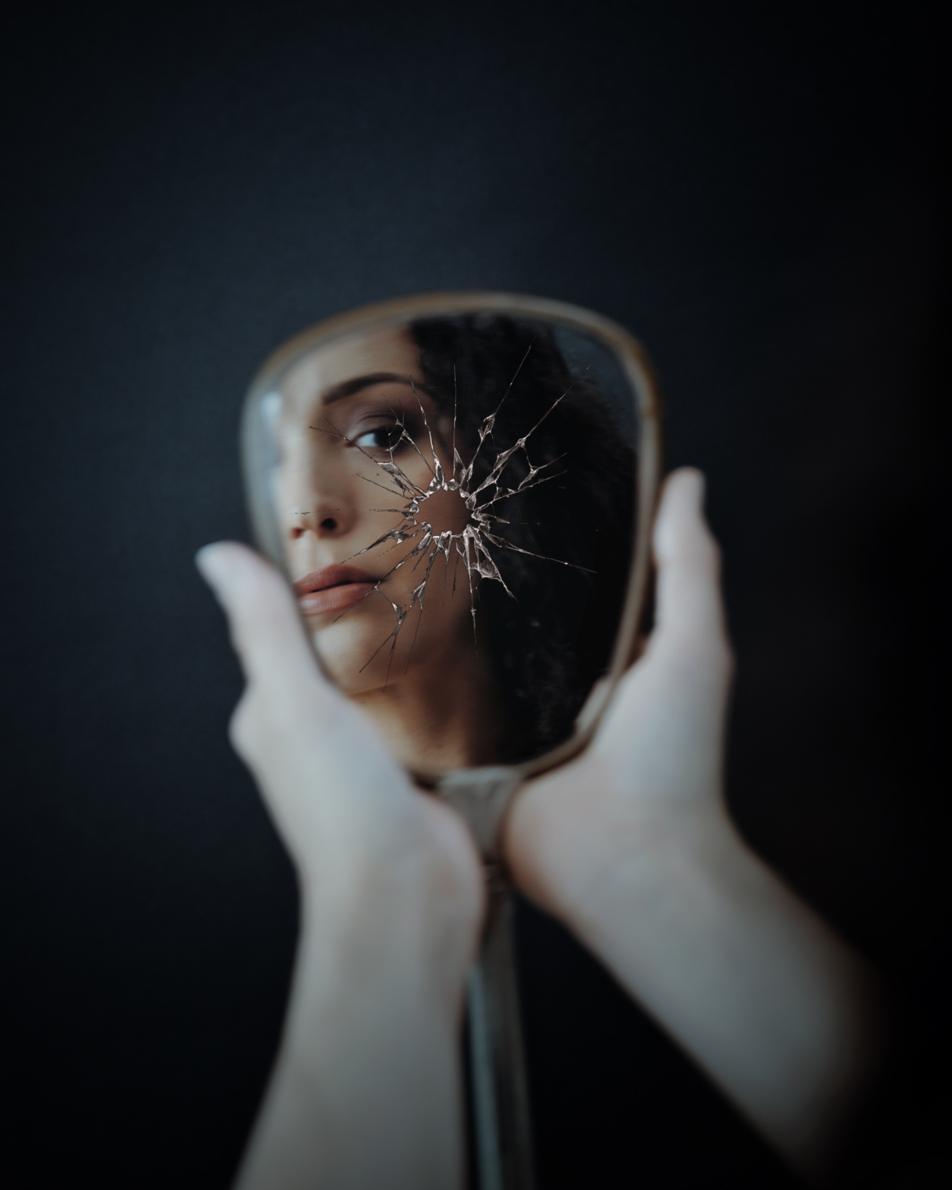 A woman looking at her reflection in a cracked mirror. | Source: Pexels