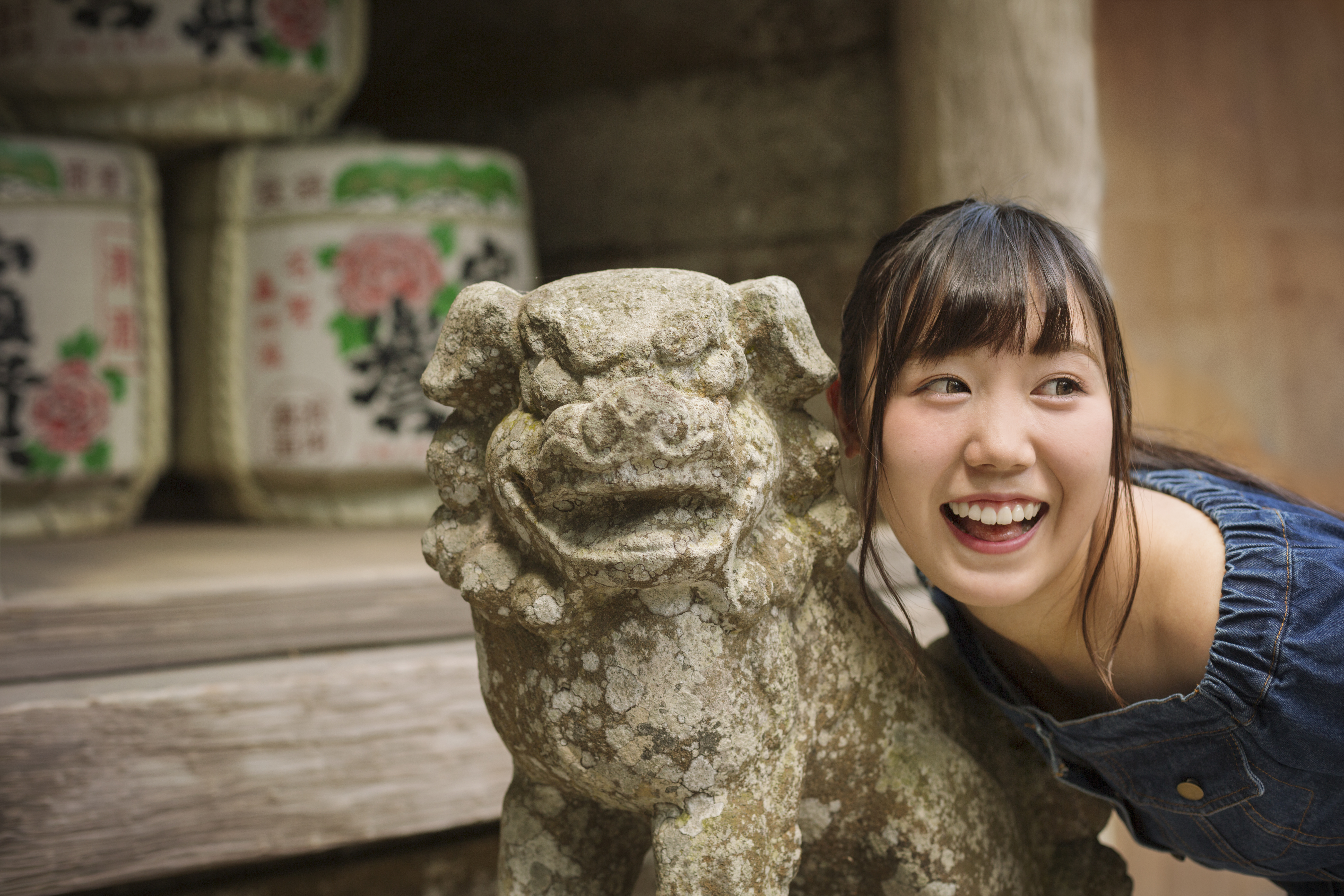 Young woman standing next to stone sculpture of lion at Shinto Sakurai Shrine, Fukuoka, Japan. | Source: Getty Images