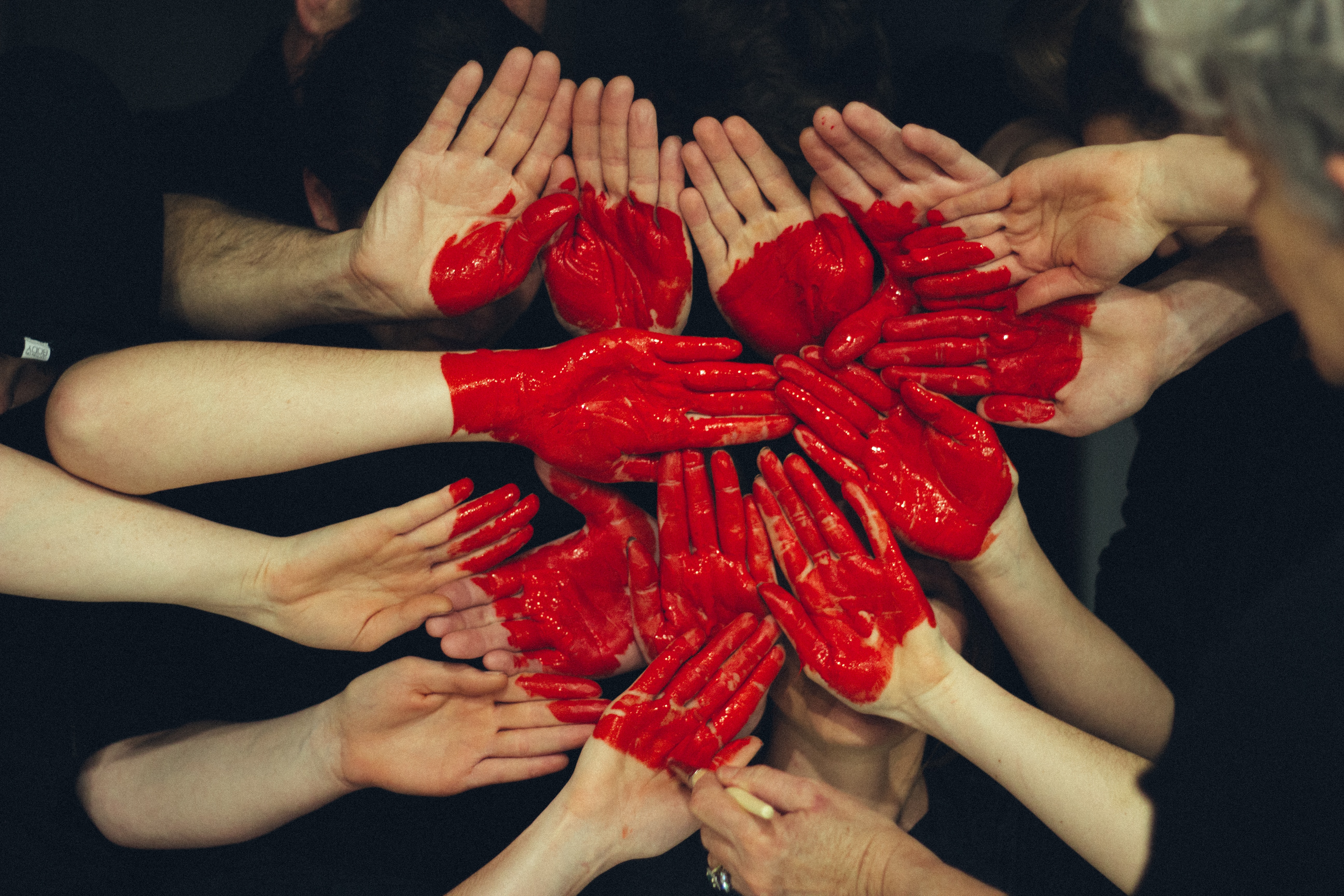 A number of individuals putting their painted hands together to form a picture of a heart. │ Source: Unsplash