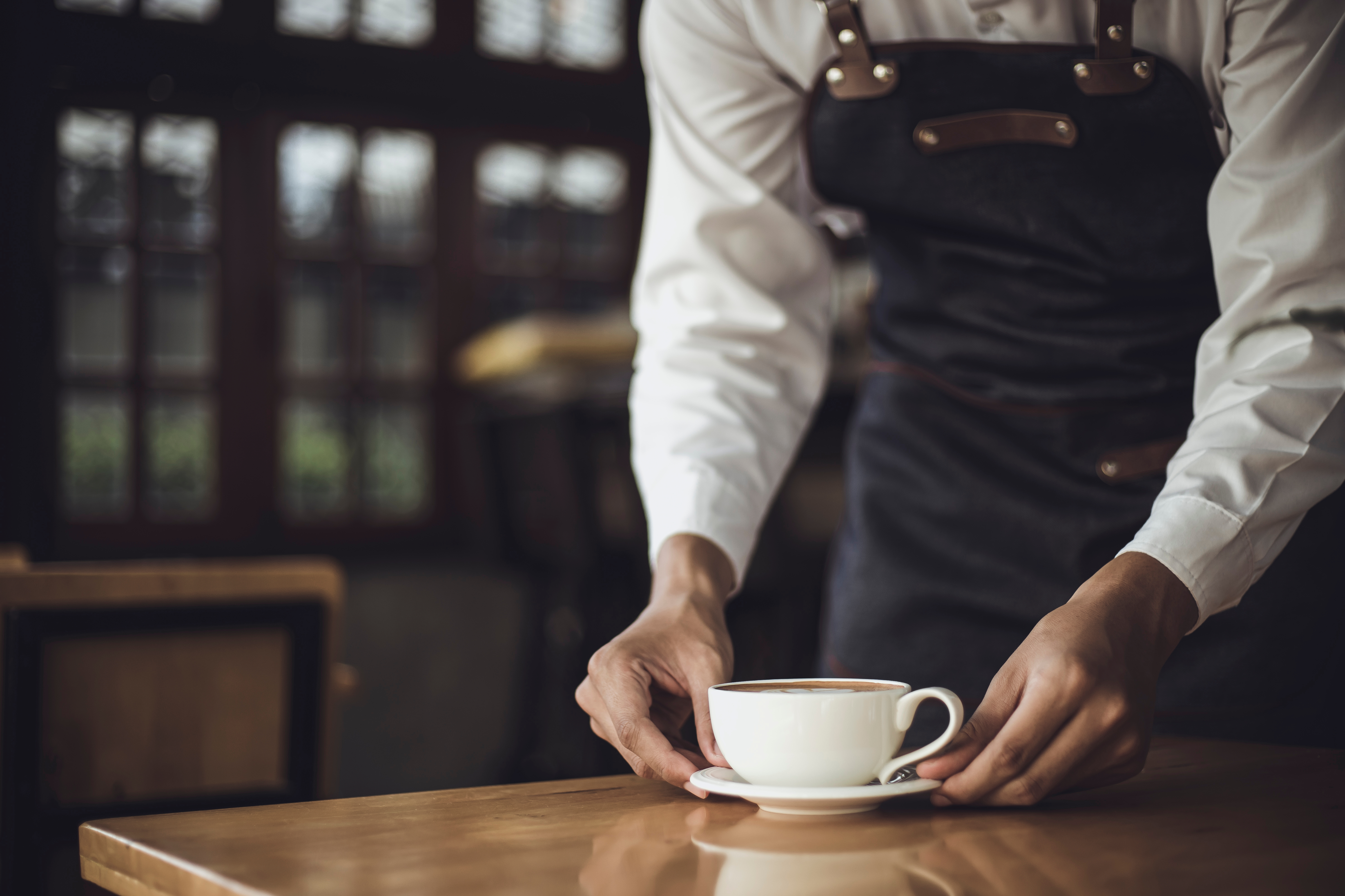 Barista masculino preparando café para un cliente en una cafetería. | Fuente: Shutterstock